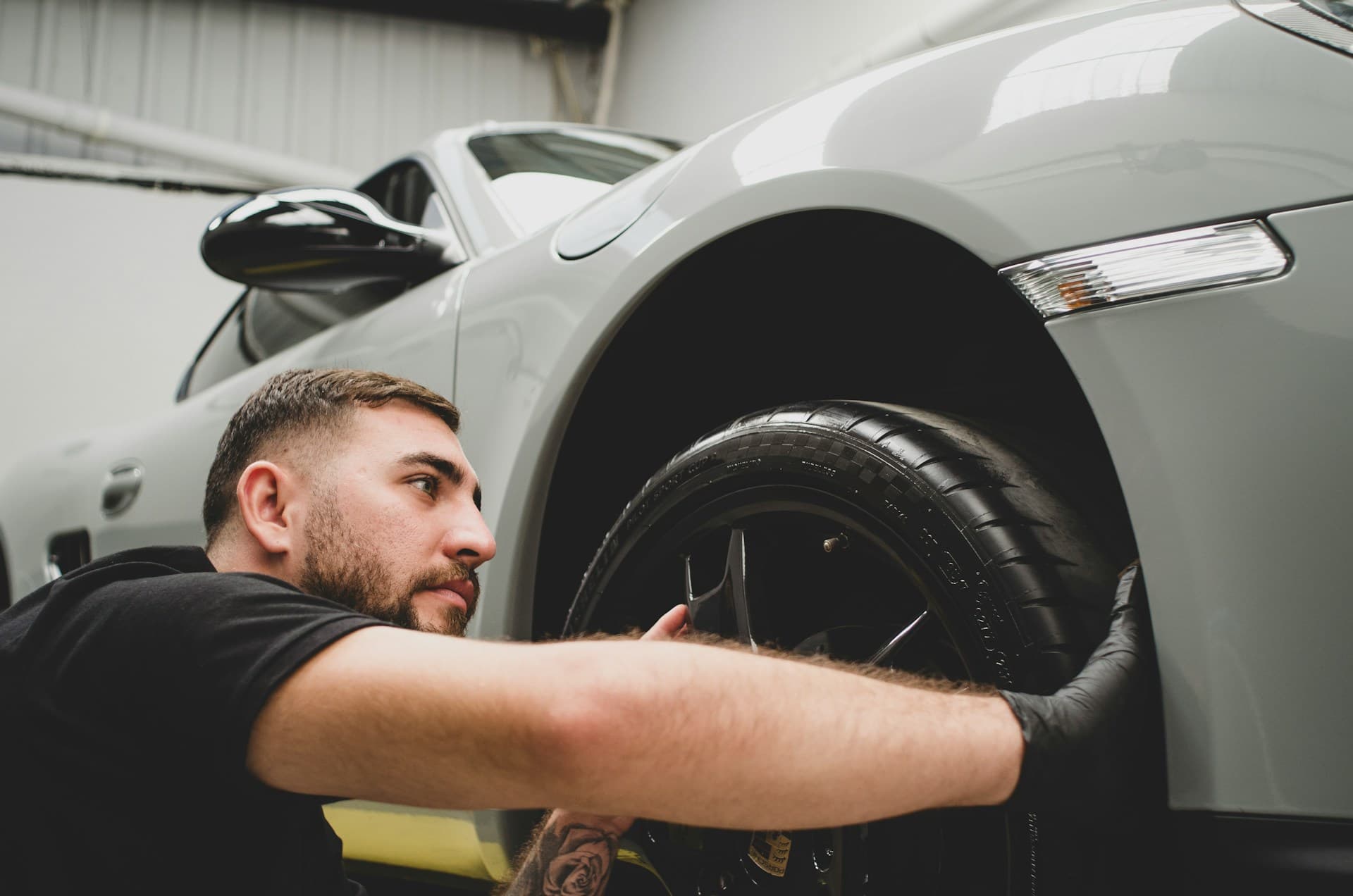Auto Gleam Details technician detailing the wheel of a white sports car