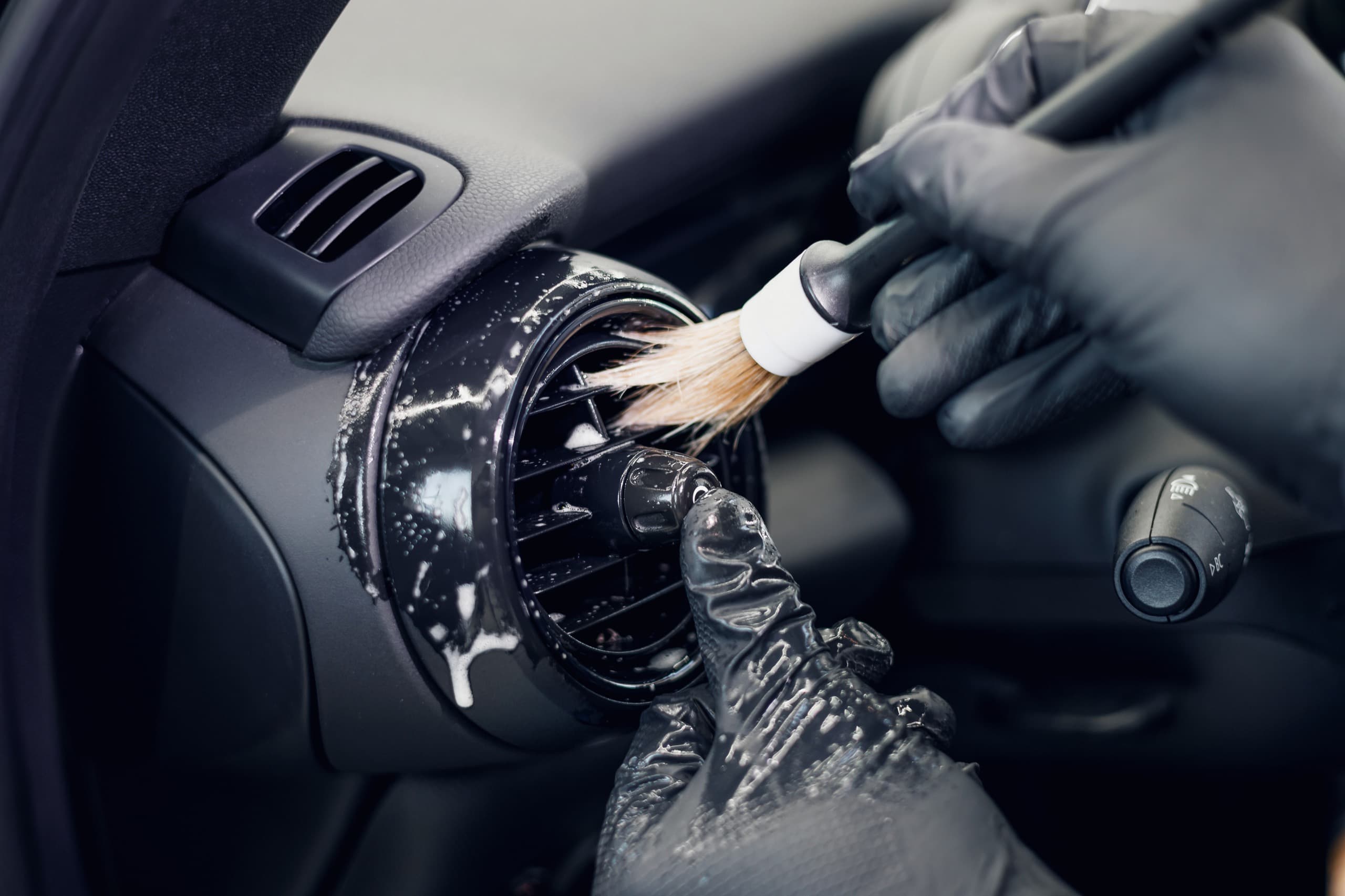 Detailer cleaning a car air vent with a detailing brush during The Cabin Refresh interior cleaning service
