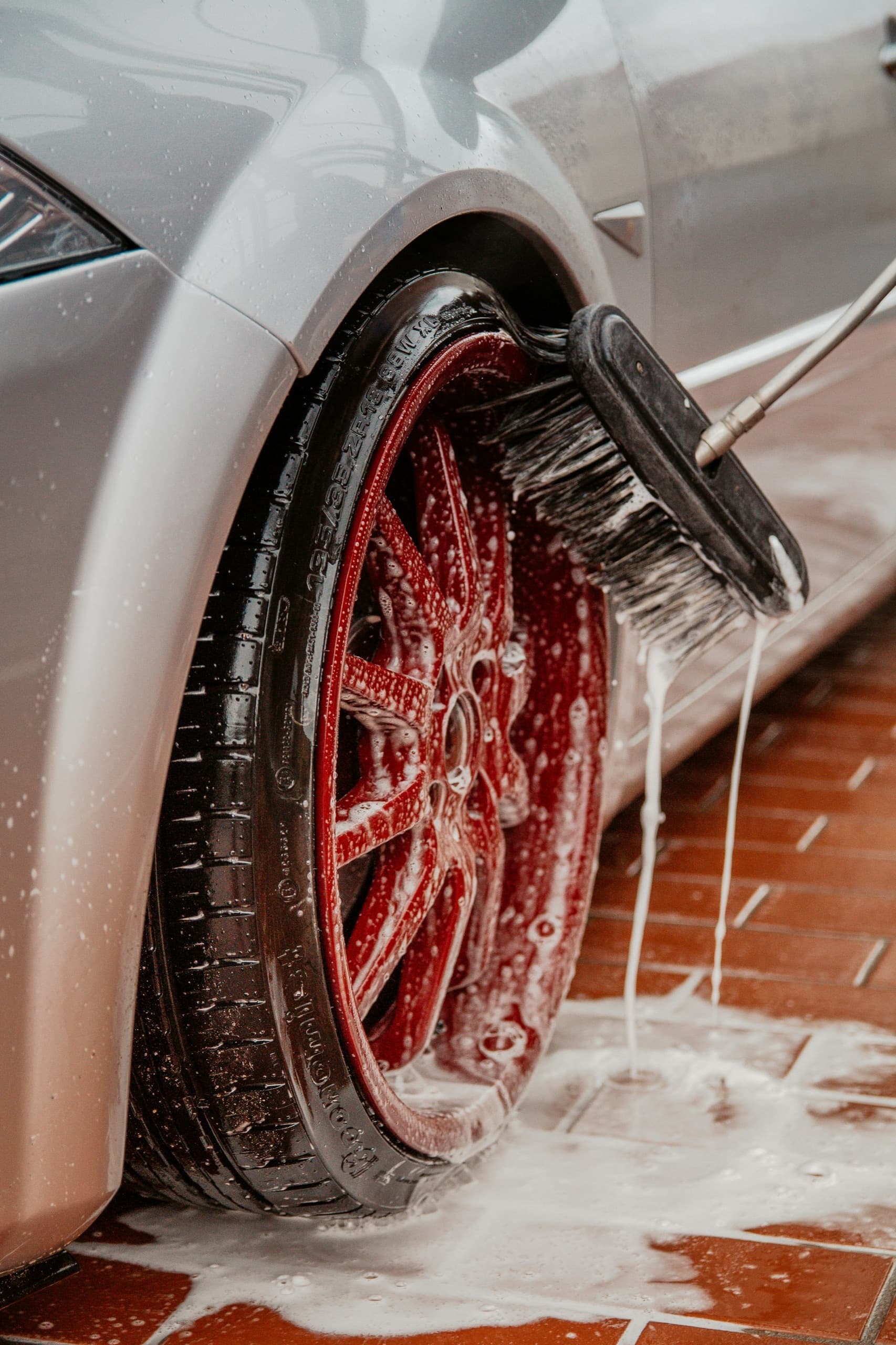 Soapy red wheel being washed during The Daily Gleam complete interior and exterior detailing service