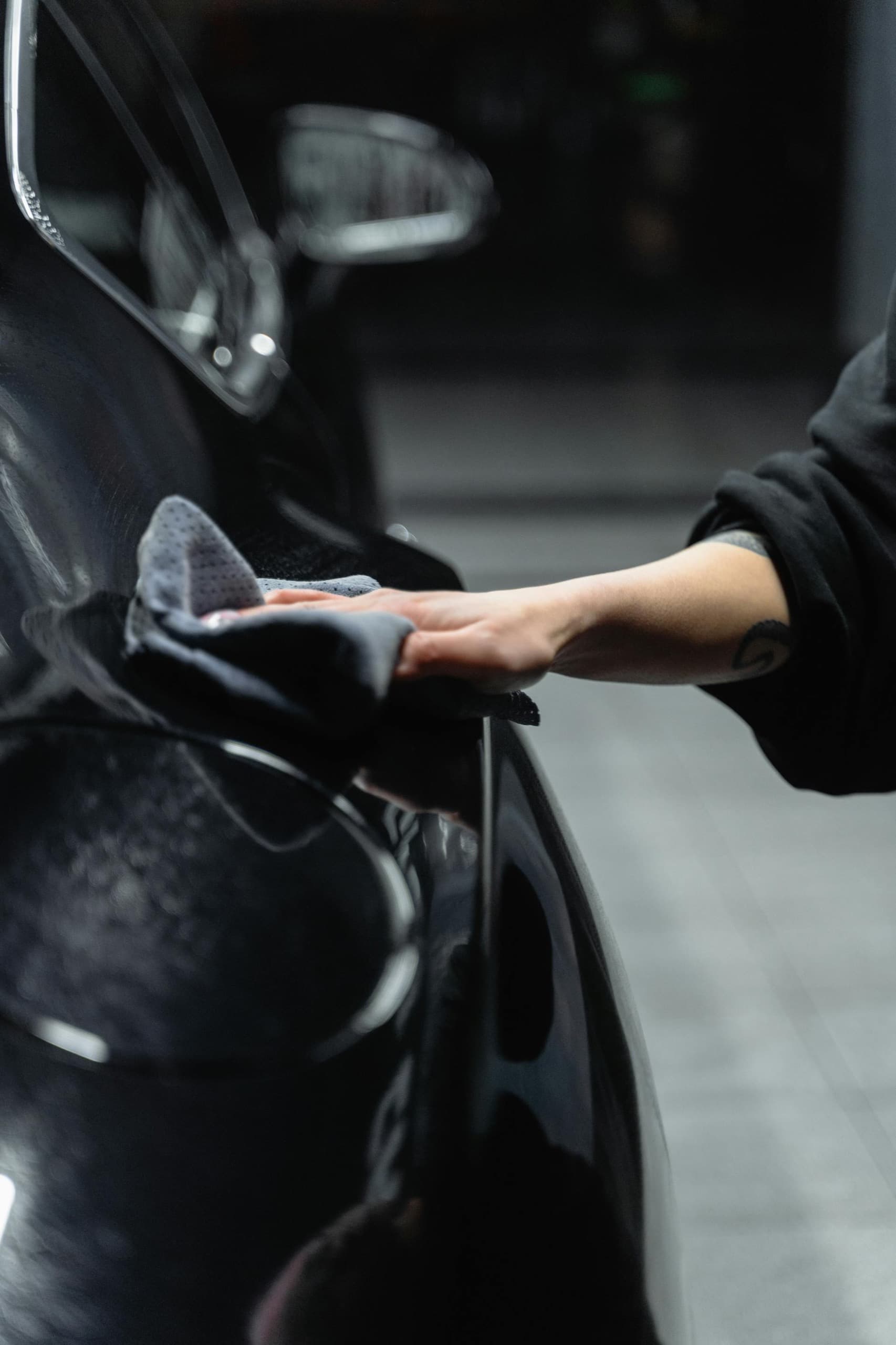 Detailer hand washing a black car with a microfiber towel during The Freshen Up exterior detailing service