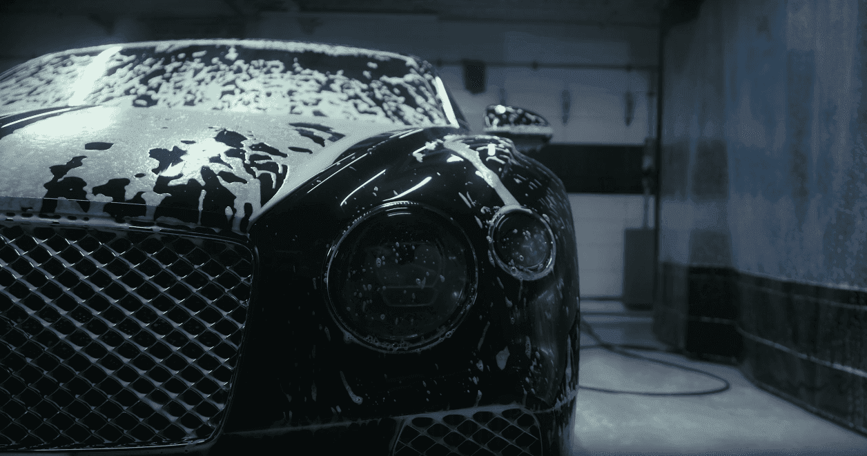 Black luxury car covered in foam during a professional detail