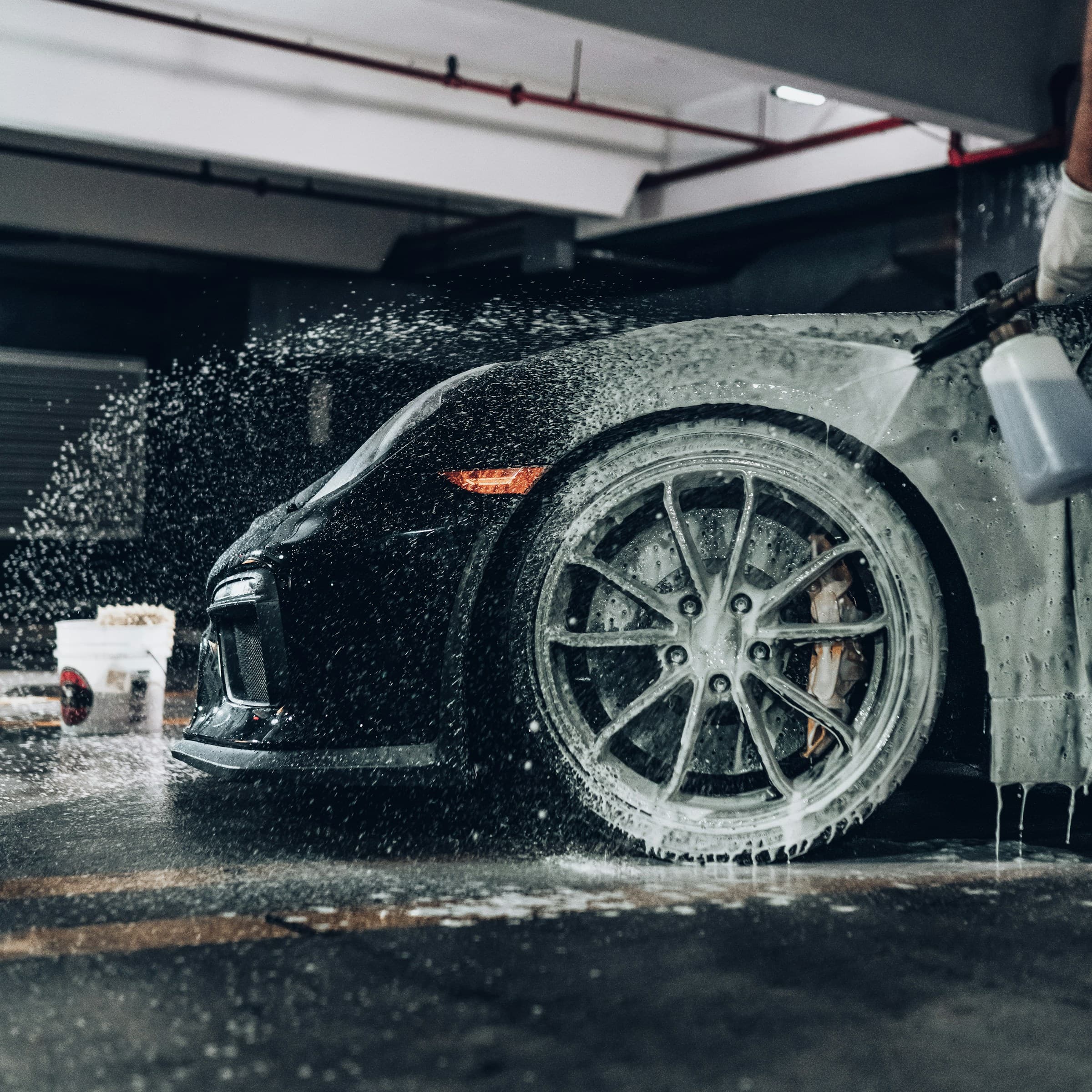 Wheel of a car being deep cleaned with foam and water